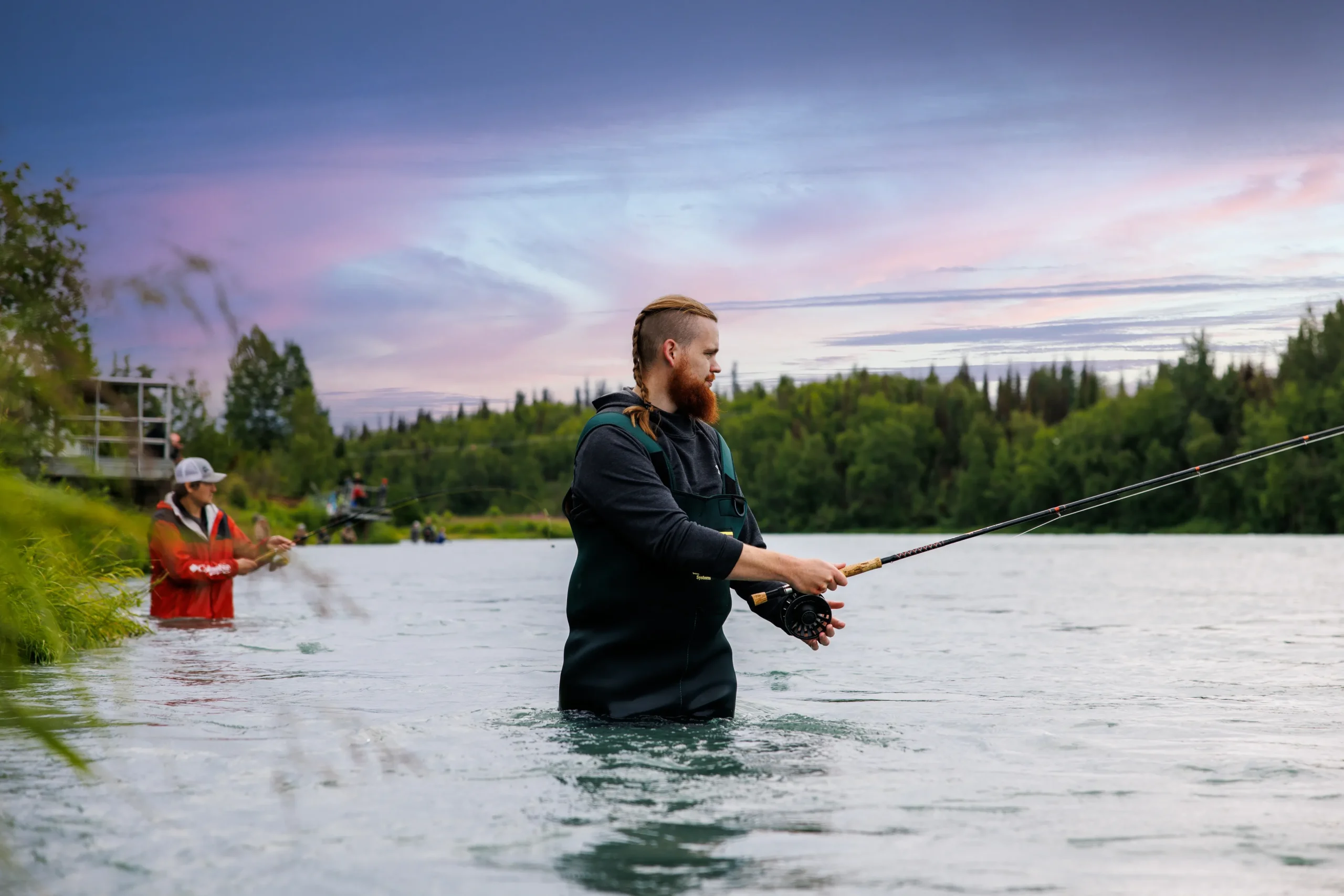 Kenai River angler fly fishing in waders with Alaska Mountain Range backdrop